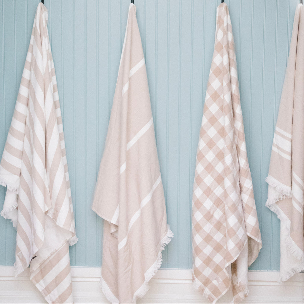 Set of matching beige beach towels hanging. Gingham tan beach towel.