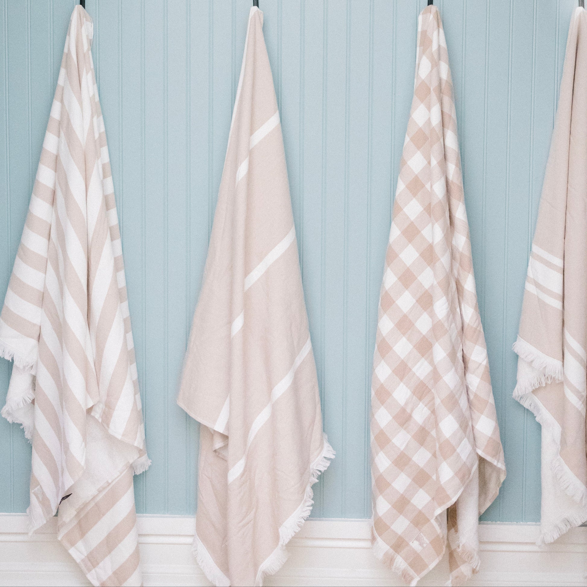 Set of matching beige beach towels hanging. Gingham tan beach towel.