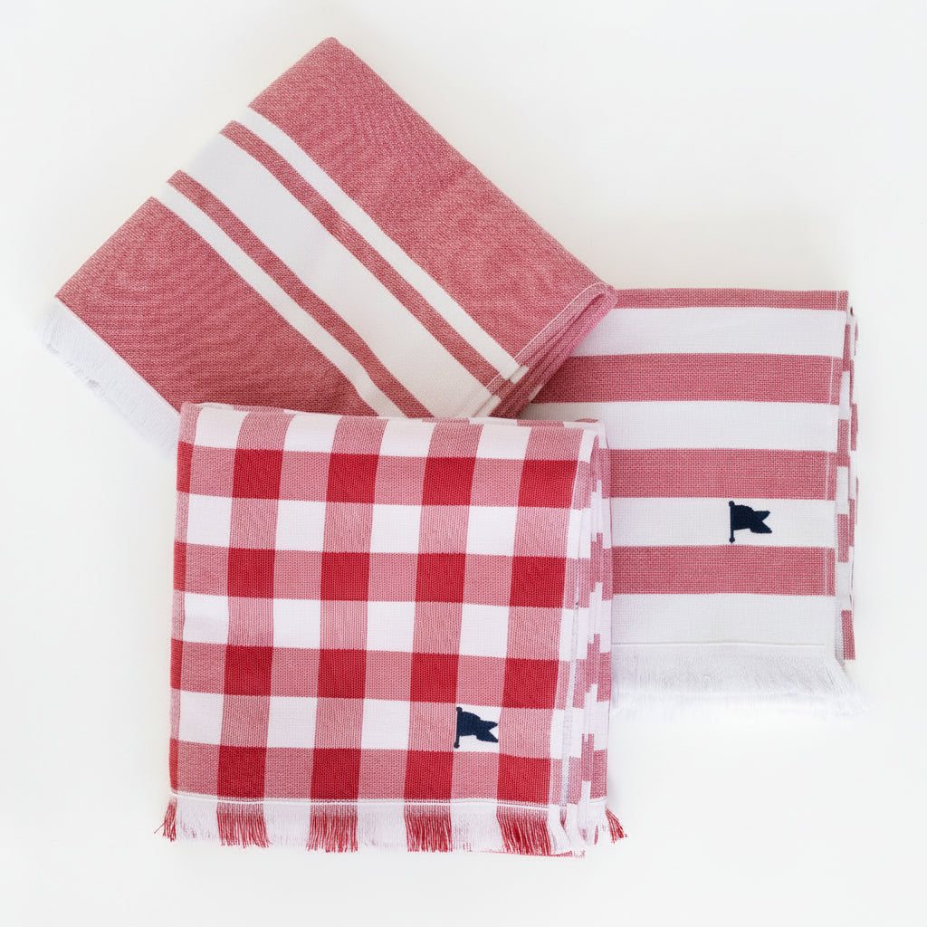 Three matching red towels, one striped and one checkered, one with a triple stripe