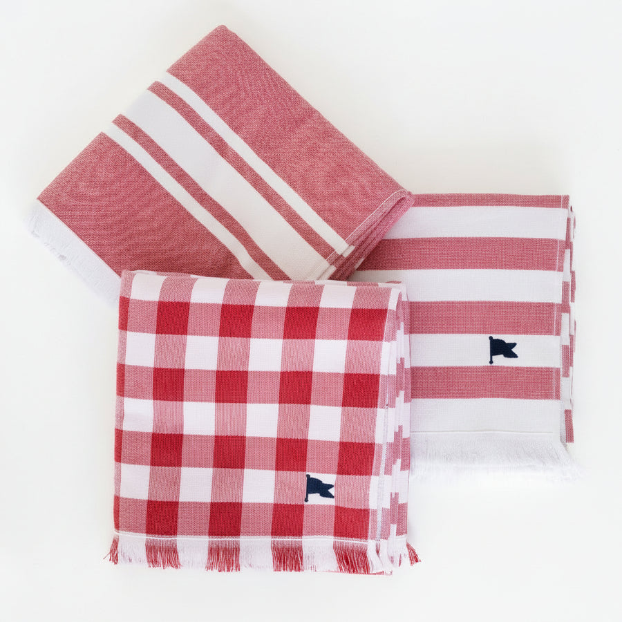 Three matching red towels, one striped and one checkered, one with a triple stripe