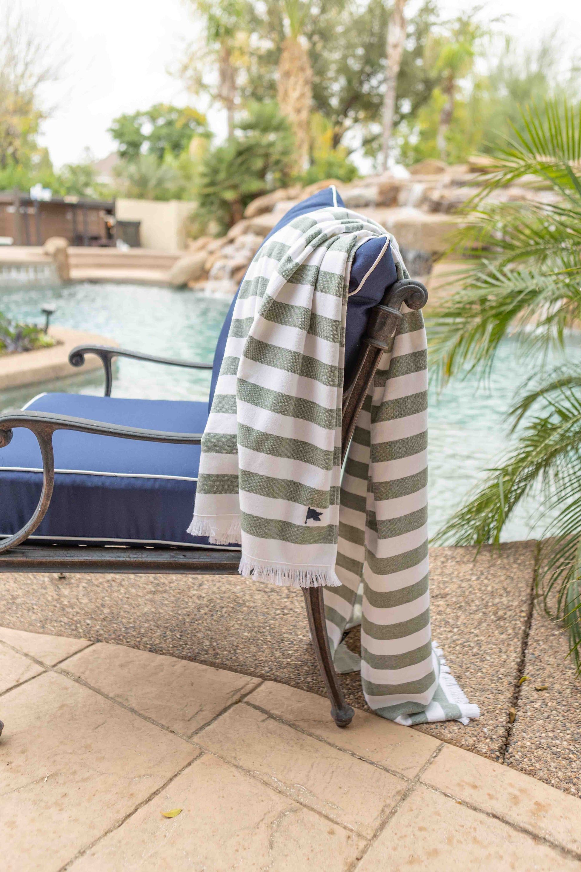 Striped beautiful luxury beach towel draped over a lounge chair by a pool