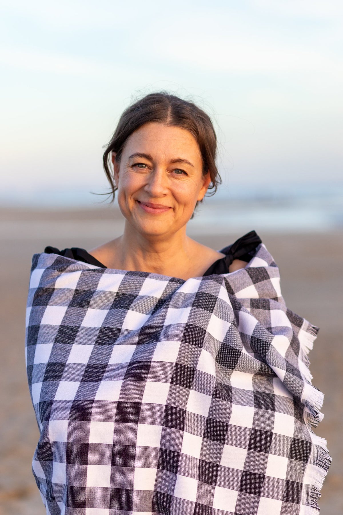 Jessica, founder of Banner Beach, wrapped in a navy Carolina Gingham towel on the beach